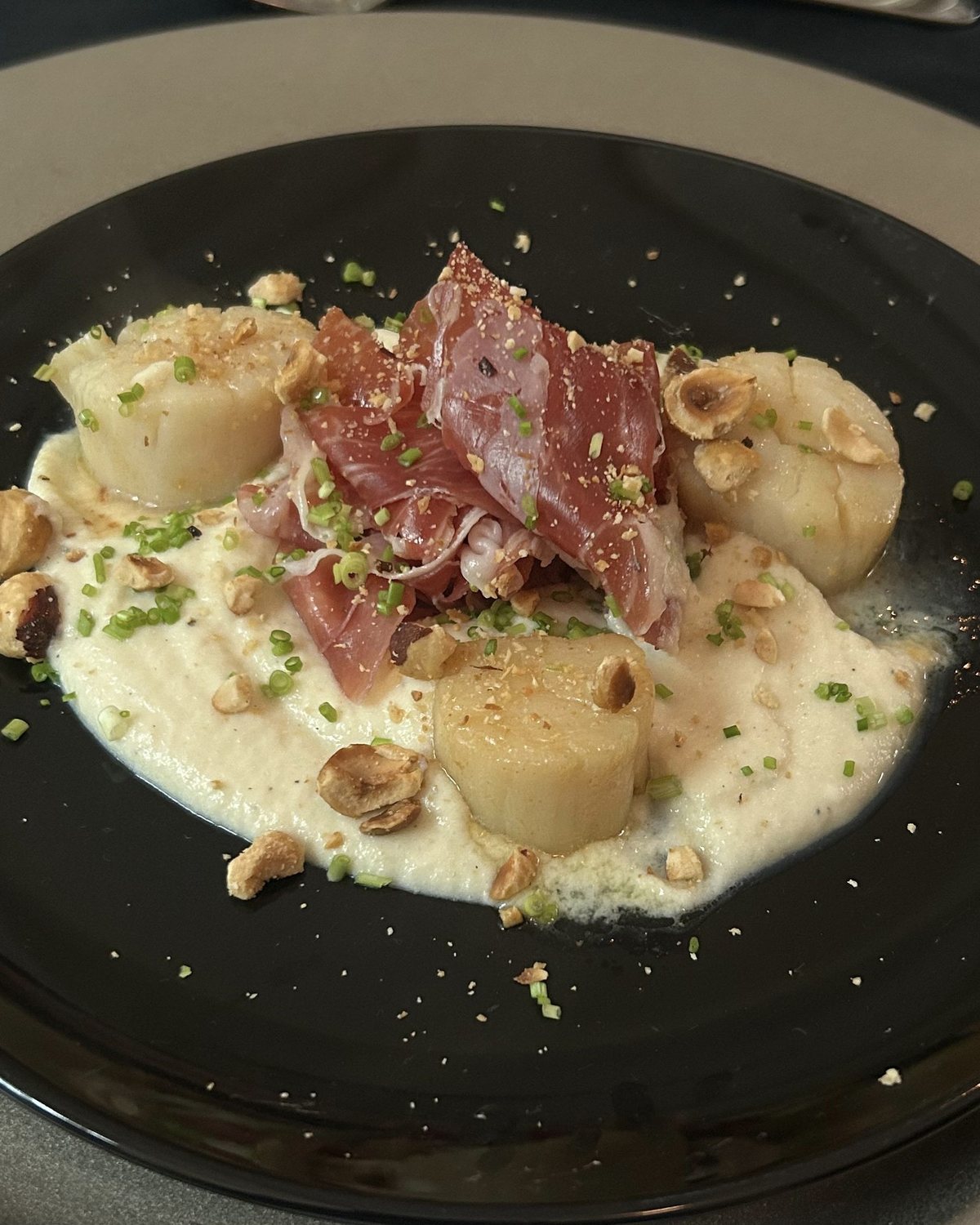 Coquilles met rauwe ham en hazelnoot op een lichte creme